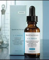 SkinCeuticals C E Ferulic skincare serum bottle with dropper and packaging on a reflective surface.