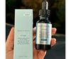 SkinCeuticals P.TiOX skincare serum bottle and packaging held in a hand with a blurred background.