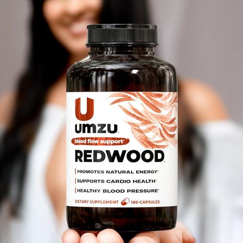 Umzu Redwood supplement bottle held by a person with a blurred background