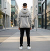 Light oatmeal Fear of God Essentials hoodie from THE EA STORE, shown in a cozy, casual fit with a front pocket and hood.