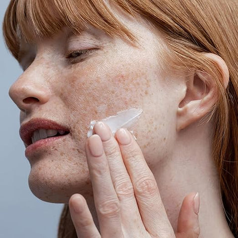 Woman applying cream to her face with a blurred background