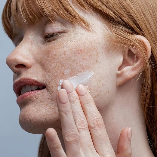 Woman applying cream to her face with a blurred background