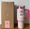 Pink Stanley 40 oz Quencher H2.0 insulated tumbler with handle and matching box on wooden surface, soft pink and fuchsia design