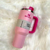 Pink Stanley Quencher H2.0 FlowState Tumbler 40oz with straw on white fluffy surface, vibrant flamingo Barbie pink color.