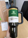 Black Stanley Wicked x Target Elphaba 40oz Flowstate Quencher Tumbler with green lid held in hand on wooden surface.