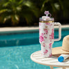 Floral-patterned Stanley x LoveShackFancy 40oz Ribbon Rosa FlowState H2.0 tumbler with straw on a table near a pool