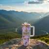 Floral-patterned Stanley x LoveShackFancy 40oz Ribbon Rosa FlowState H2.0 tumbler on rock with mountain landscape background