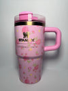 Pink floral Stanley Ibiza Sunset 20oz tumbler by THE EA STORE on light gray background, showcasing its vibrant design and size.