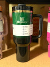 Green Stanley Wicked x Target 40oz Elphaba H2.0 FlowState water bottle on wooden surface with blurred background.