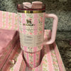 Pink floral Stanley x Love Shack Fancy 40oz Quencher Tumbler on matching pink surface with textured background, spill-proof stainless steel design.